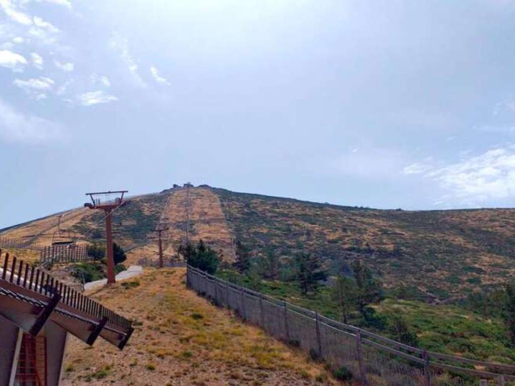 Poste del telesilla de la estación de Navacerrada con las pistas sin nieve