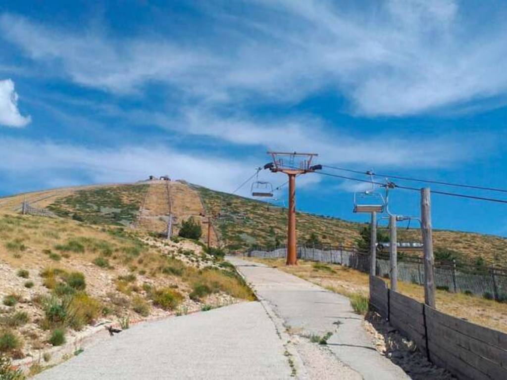 Poste del telesilla de la estación de Navacerrada con las pistas sin nieve